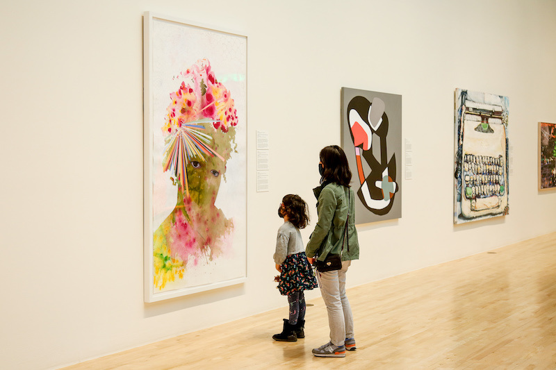 Woman and daughter looking at an artwork.