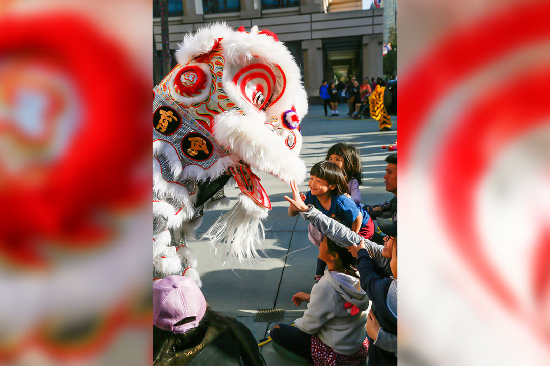 Kids clamoring over a lion dancer.