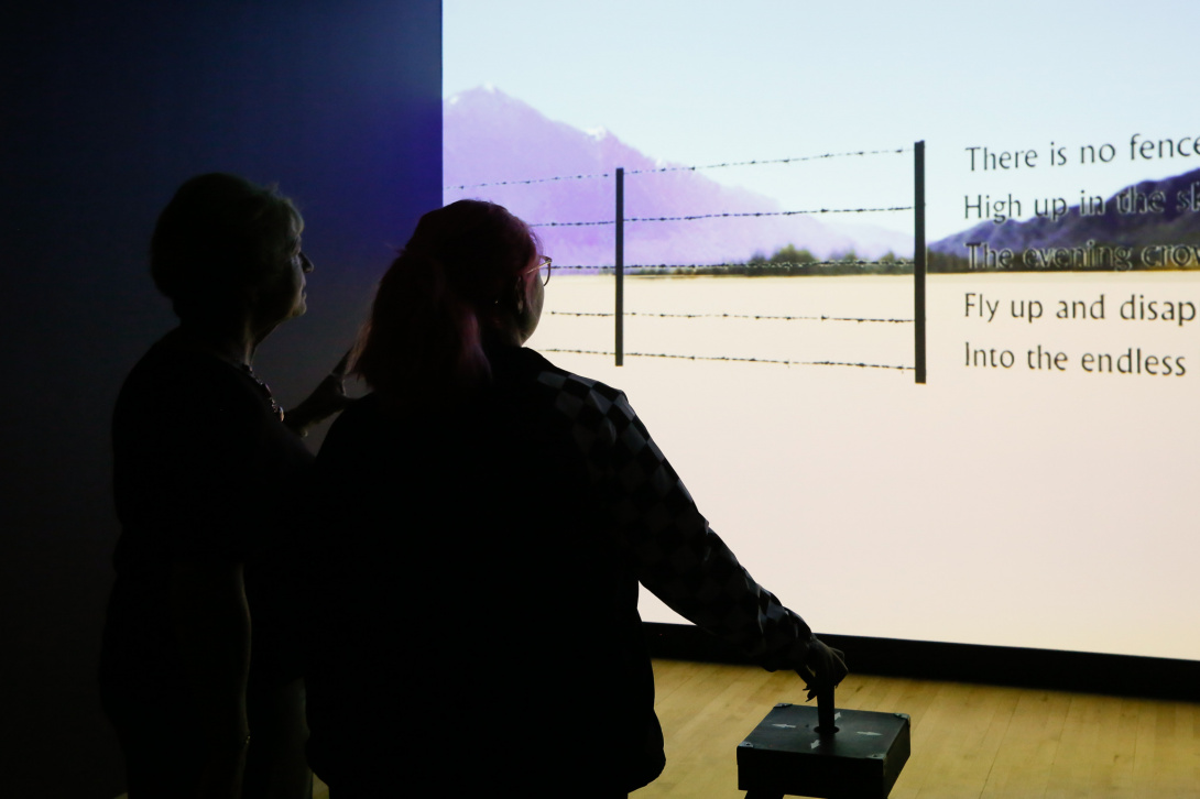 Older woman with short hair talking with a younger woman with pink hair in a dark digital installation.