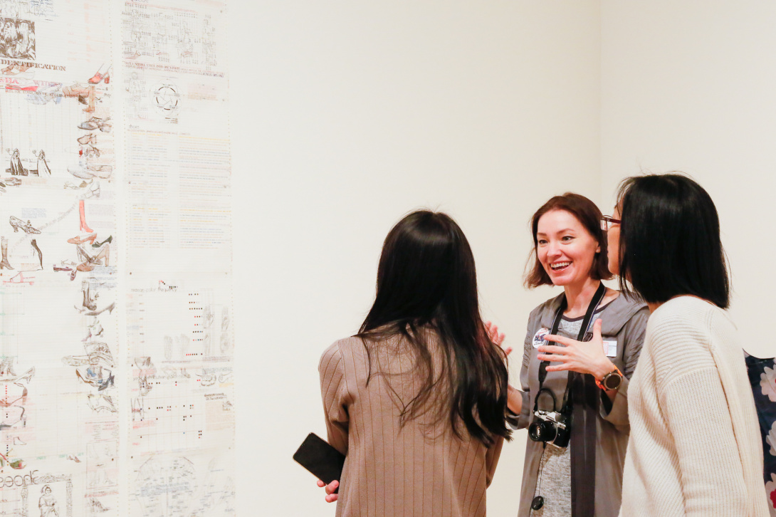 Brown-haired docent talking to two women in a gallery.