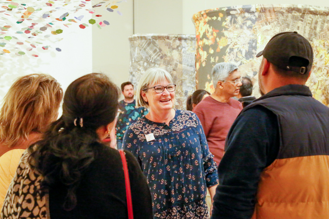 Docent chatting with visitors in a colorful gallery.