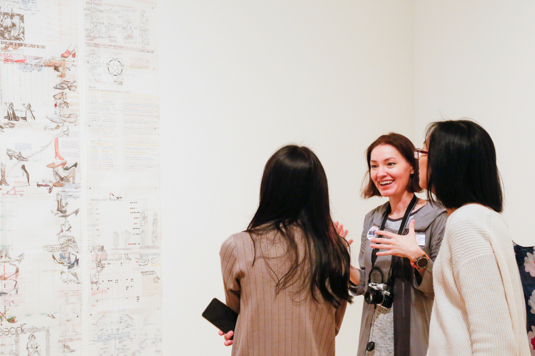 Three women interact while looking at art. 