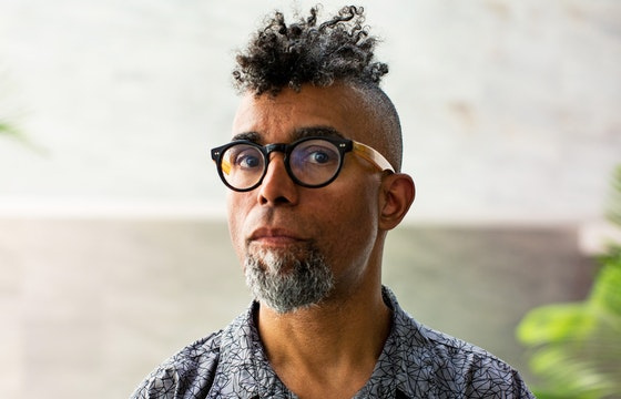Man wearing glasses with curly hair mohawk.