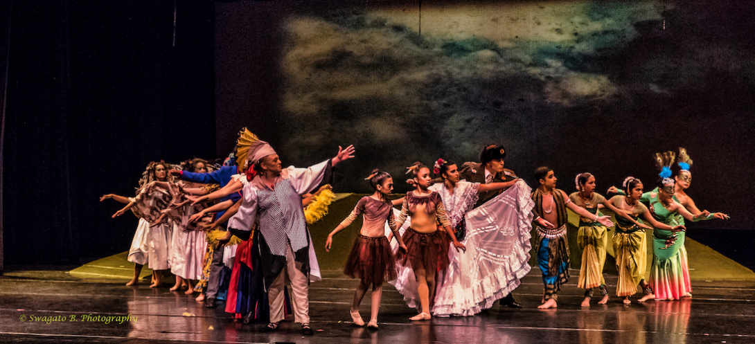 Performers looking right while in different cultural costumes on a stage.