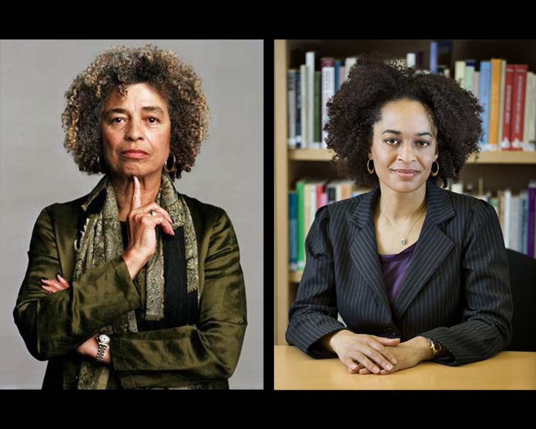 Woman on left with salt and pepper curly hair, wearing a blazer and scarf. Woman on right, with curly dark hair, sitting down on a desk.