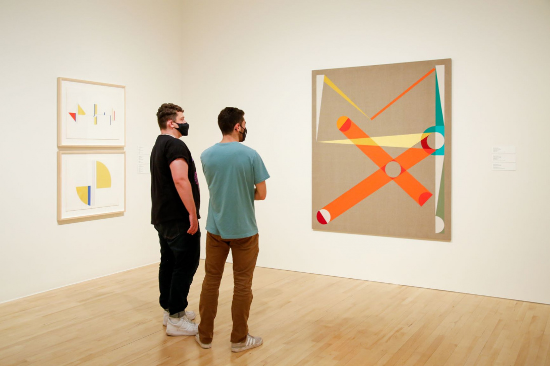 Two young men looking at an abstract painting in a gallery.