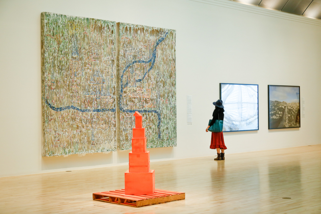 Visitor in red dress looking at a large scale artwork.