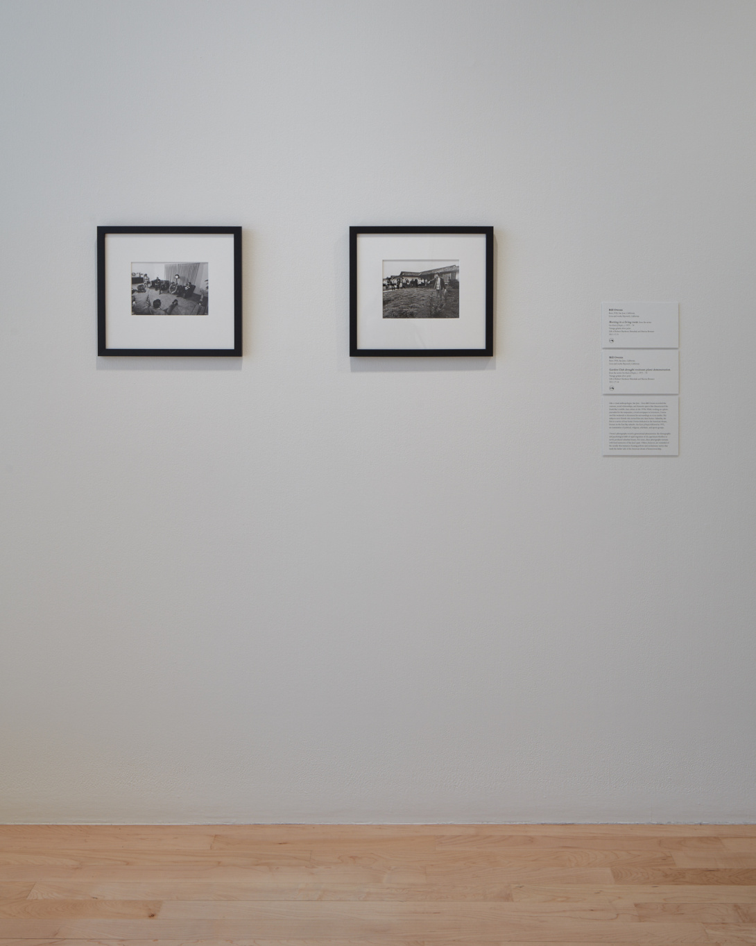A white wall with two framed black and white photographs and three small text panels.