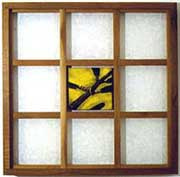 A wooden frame containing a grid of nine small white square windows or openings. The center square contains an abstract yellow and black image.