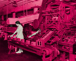 A bright fuschia composition of large machinery with a conveyor belt and boxes evenly spaced on the belt. The work being done is unknown, but a women collaged in black and white, with hair tied back and white sturdy shoes, is doing it.