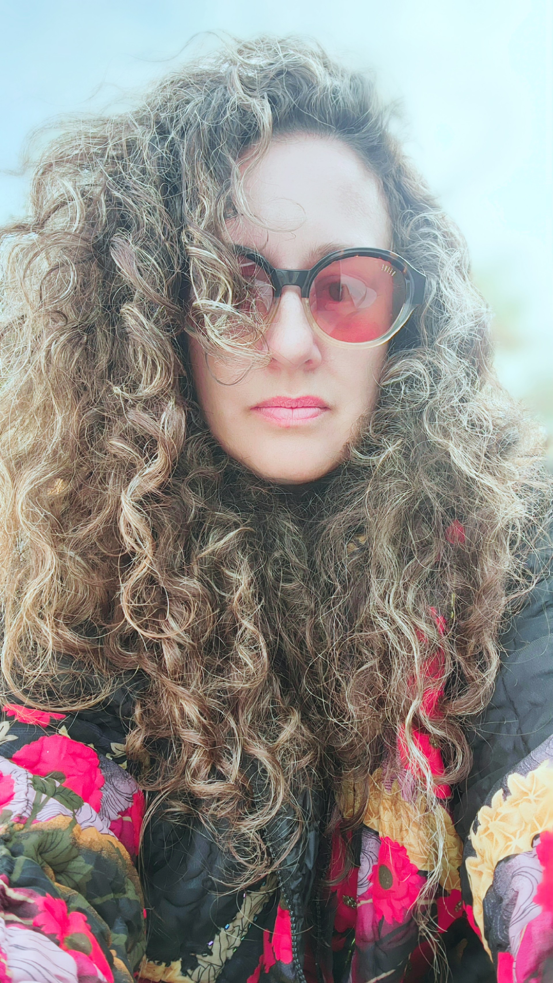 a woman with curly hair wearing rose-colored glasses