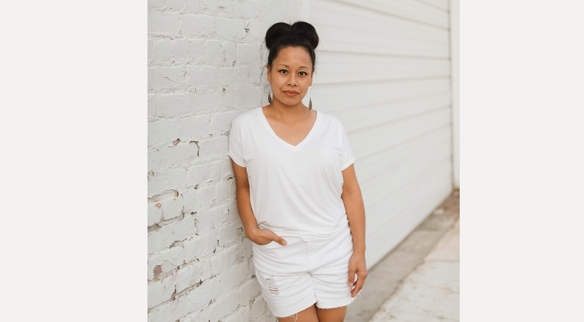 vietnamese woman wearing white against a white brick wall